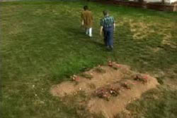 Two men walking away from two freshly filled in graves.