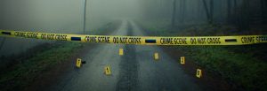 Crime scene tape in front of foggy road, numbers 7 1 2 0 on evidence markers