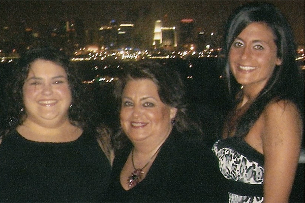 Mother and two daughters with city lights behind them