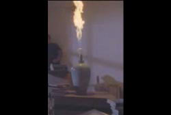 A gas latern on a table shooting out a pillar of fire.