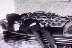 A corpse laying on an ornate black leather couch.