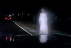 A woman in a bright white dress walking down a busy road at night.