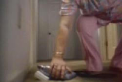 A woman in pink pants in bending down to pick up a drill off the floor.