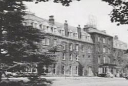 A black and white photo of a large 4 story building, an old fashioned spa.