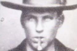 Headshot of Brushy Bill, age 17, wearing a hat and smoking a cigar.