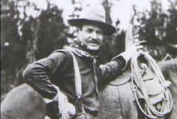William Philips in cowboy gear, standing next to a horse.