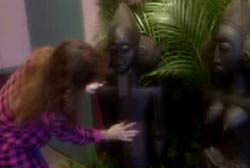 A woman in a purple flannel shirt rubbing the stomach of a fertility statue.