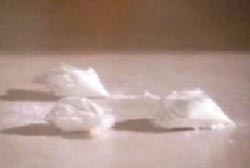 Three small plastic bags filled with a white powder on a table top.