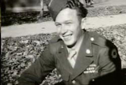 A smiling soldier in uniform, his curl hair tucked into his hat.