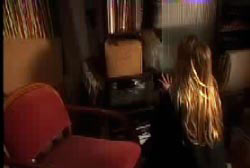 A blonde teenager searching through a living room for clues. 