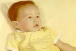 A baby in a yellow outfit on a yellow bed.