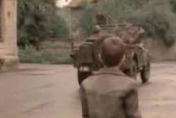 A small caucasian boy is watching as soldiers drives away in a jeep.