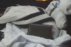 A white sweater and a wallet are on a car seat.