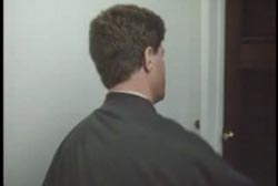 A man in a black coat knocks on a door.