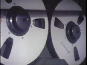 A vintage recorder, the two large reels of tape spinning.