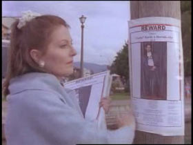 Denise Allen putting up missing posters with a reward on a street pole.