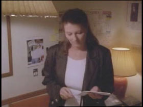 Denise Allen standing in her living room holding a envelope.