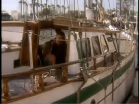 A sailboat with green trim and John Paul is hunched over in the interior cabin.