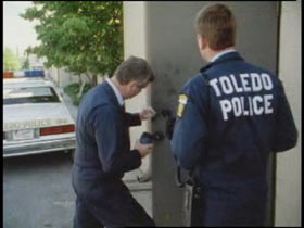 Two Toledo police officers are trying to pull fingerprints off a door.