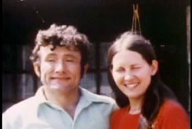 Dottie Caylor posing with her husband, Jule Caylor. He has short curly dark hair and a collared shirt.