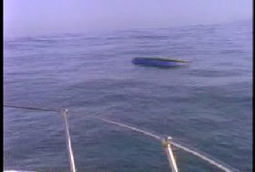 An overturned boat is bobbing in the water.