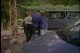 Three people are walking towards a large van in the background. 