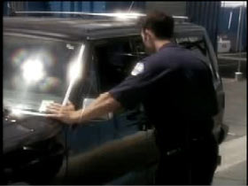 A police officer stops a black SUV and questions the driver through the open window.