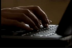 Two hands typing on a keyboard of a black laptop.