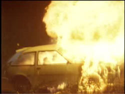 A two door compact car on fire.