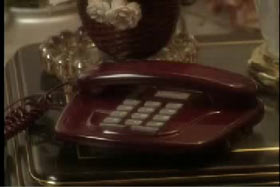 A red landline phone on a mirror top table.