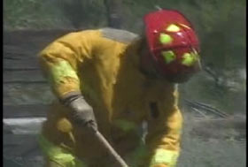 A firefighter bending down to shift through the debris.