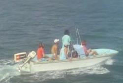 Five people wearing baseball caps in a small motor boat as it travels across the water.