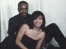 Niqui is posing with her fiance, a African American man wearing a black shirt and dark pants.