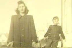 A vintage photo of a woman standing next to a child. They are both in dark jackets.
