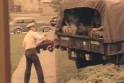A man in uniform loading something into the back of a military van.