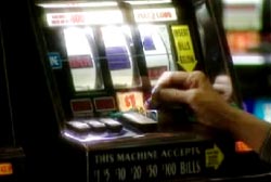 A person slipping a coin into a slot machine