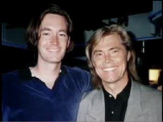Joe with his arm around his father, Dennis Cole. Both had long hair and are smiling