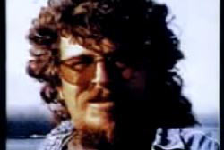 Tom Roche with long curly hair beard and glasses