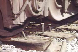 A close up on the tracks where several large nails are sticking up out of the tracks.