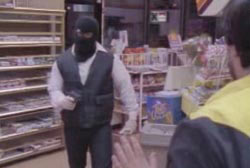 A man in a black ski mask pointing a gun at another man in a grocery store.