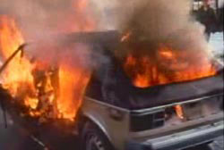 A small compact car engulfed in flames.