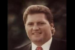 Smiling Dick Hansen in a suit and tie