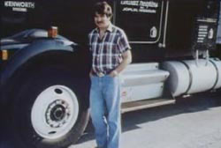 Smiling Dwayne McCorkendale with a mustache standing next to his semi-truck