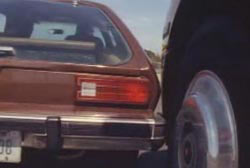 A brown pinto car bumping into the front of a semi truck