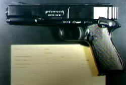 A small pistol on a black table with a yellow note under it