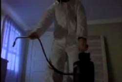 An investigator wearing a hazmat type suit performing a luminol test in the guest house