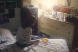 Kathy sitting on her bed in her bedroom writting something on a piece of paper