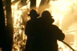 Two firefighters spraying down the Freeman home thats engulfed in flame