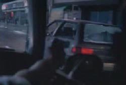 A man aiming a gun out of his passenger side window at Kevin's car