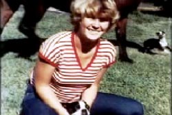 Smiling Melissa Jo Sermons with blond hair and striped shirt sitting on the ground